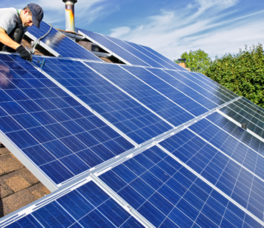 Rooftop solar panels installed on a modern suburban home under clear blue skies